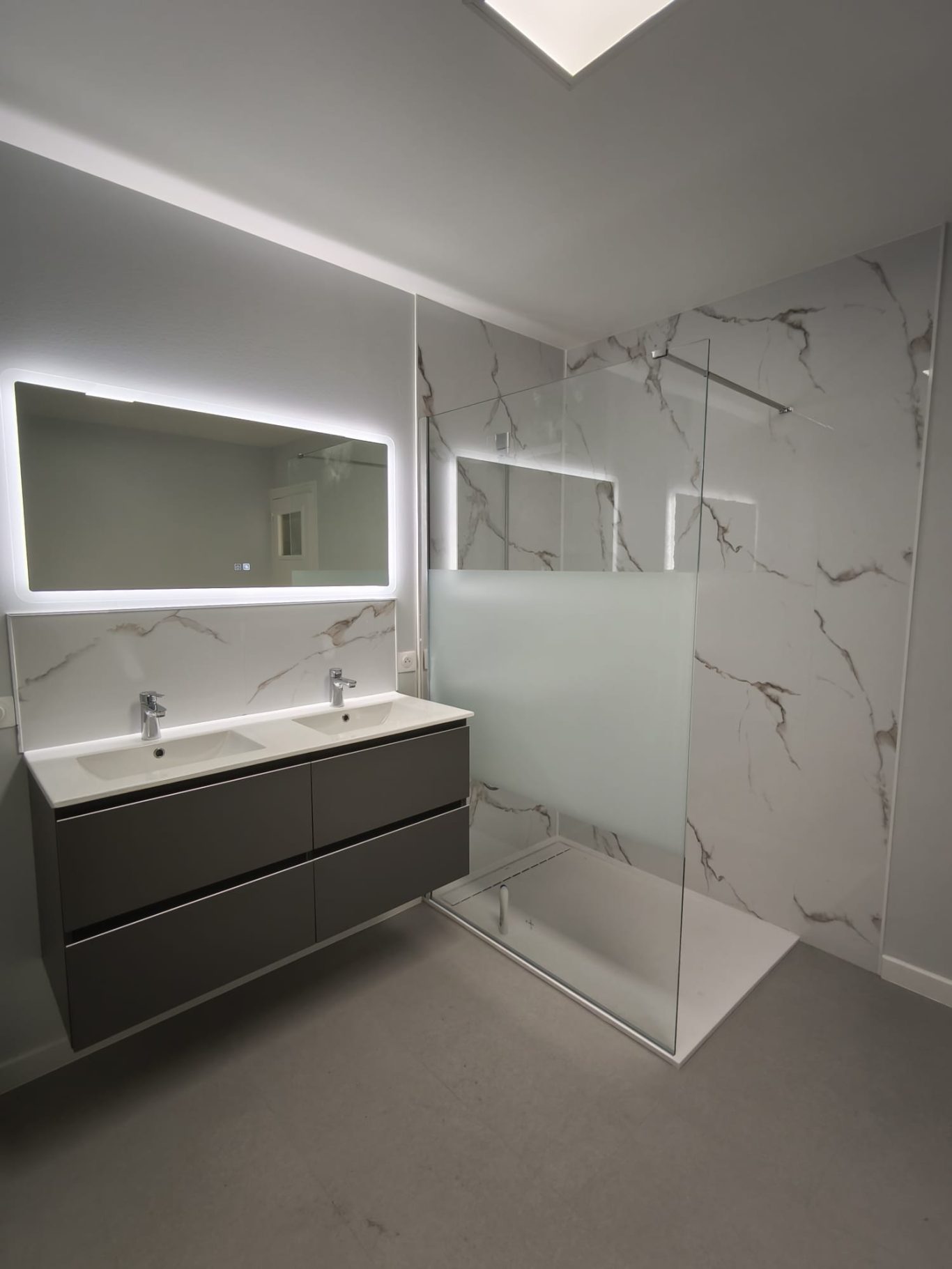 Création d'une salle de bain moderne Salle de bain moderne avec un double lavabo, miroir lumineux et douche en verre.